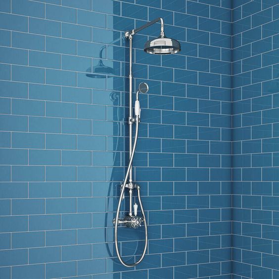 A light blue wall with brick styled tiles and an exposed luxury shower seet.