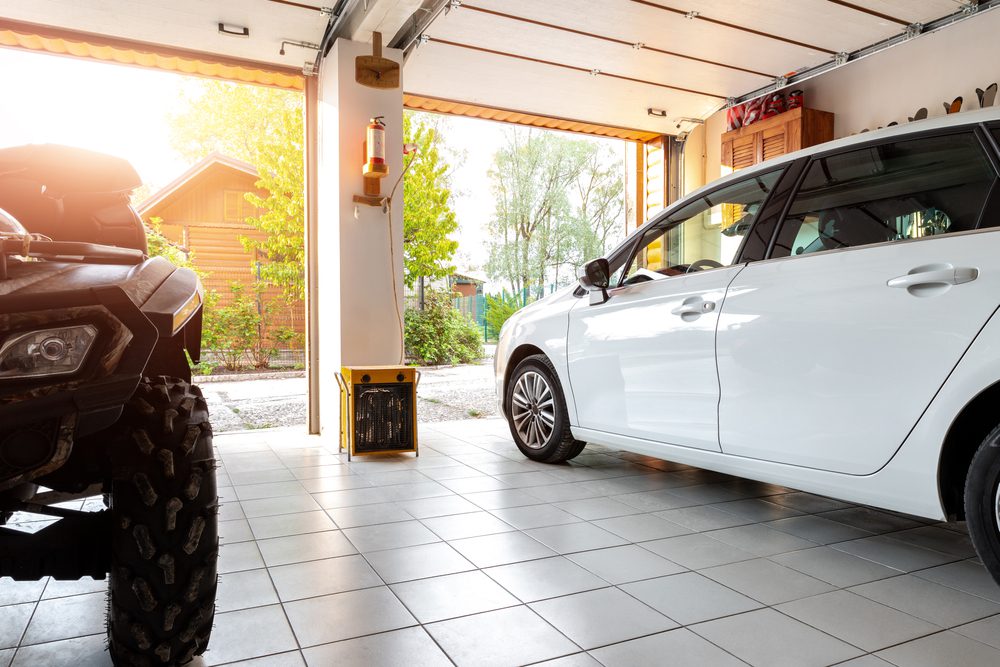 Double Door Garage With 2 Vehicles Parked Inside. The Doors Of The Garage Are Open.