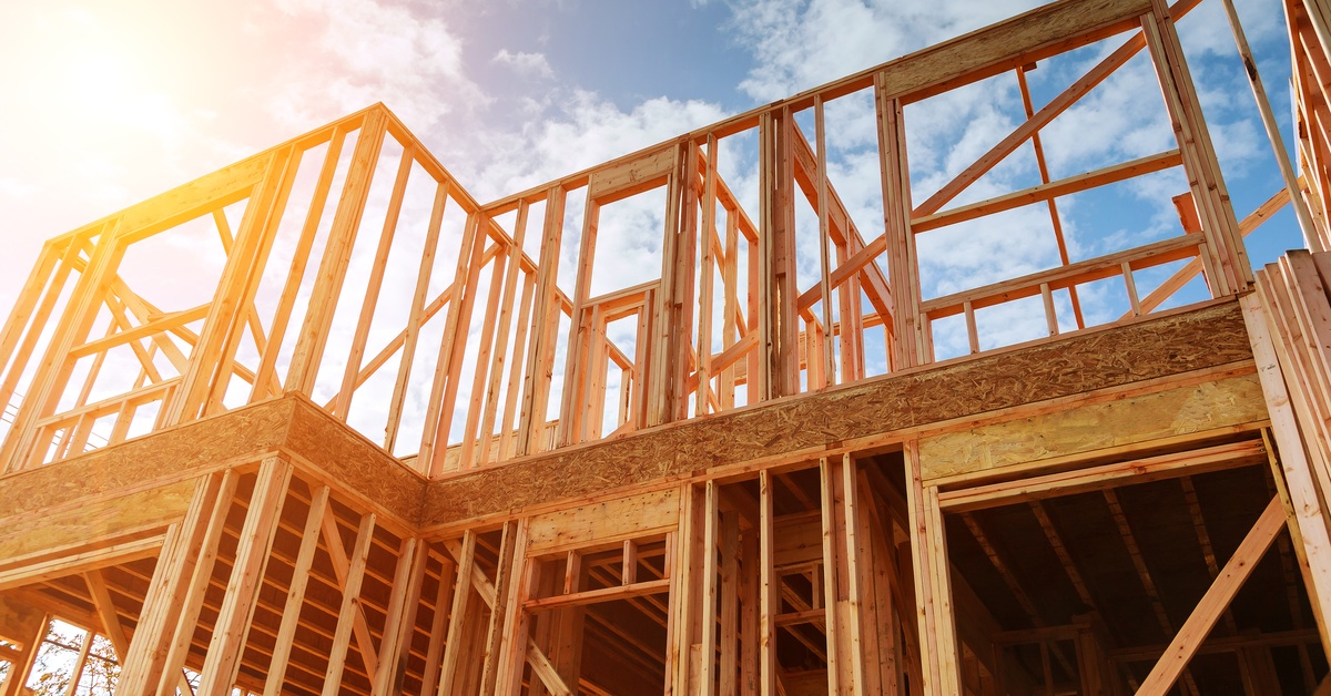 A bottom view of a large wooden two-story structure with multiple wooden beams across with a cloudy background.