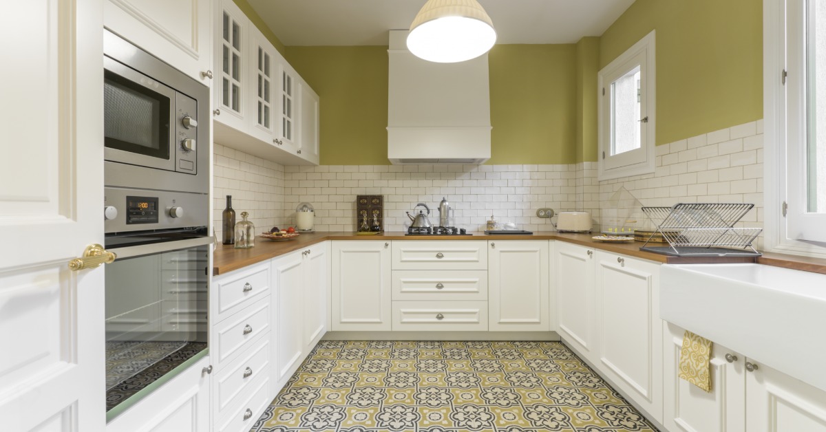 A U-shaped kitchen with a yellow floor tile, white cabinets, a stainless-steel microwave, and wooden counters.