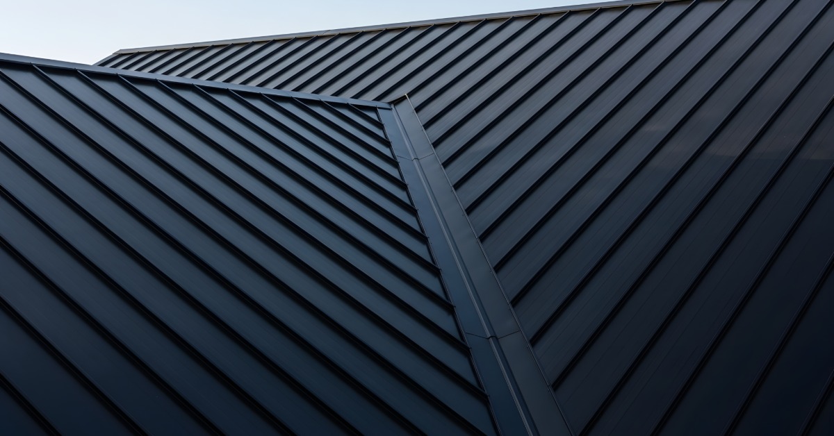 A close-up of a home’s roof with two large metal sheets with lines on different levels connecting in the middle.