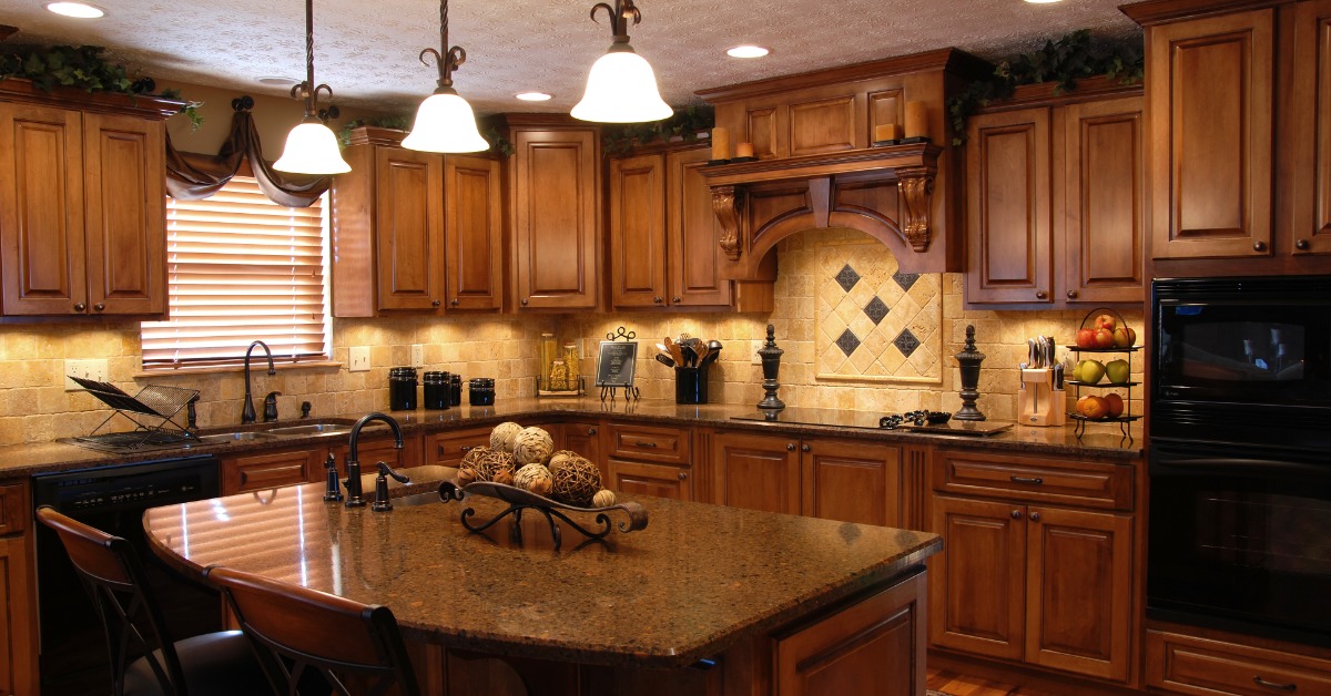 A kitchen with wooden cabinets, a small island, a backsplash with beige tiles, a black oven and a black microwave.