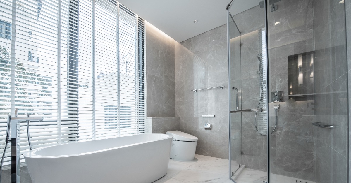 A modern bathroom with a large walk-in shower surrounded by glass panels, across from a white tub and a toilet.